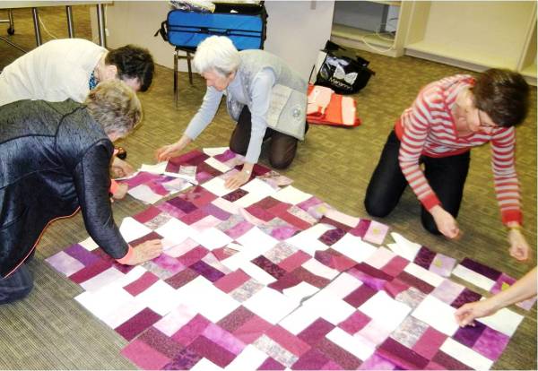 Volunteers laying out fabric pieces for a quilt top